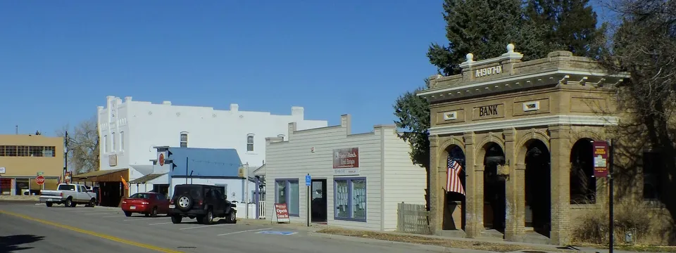 Main Street in Elizabeth, Colorado: the 1907 First National Bank building with its arched openings and the white false-front store beyond, under a clear winter sky
